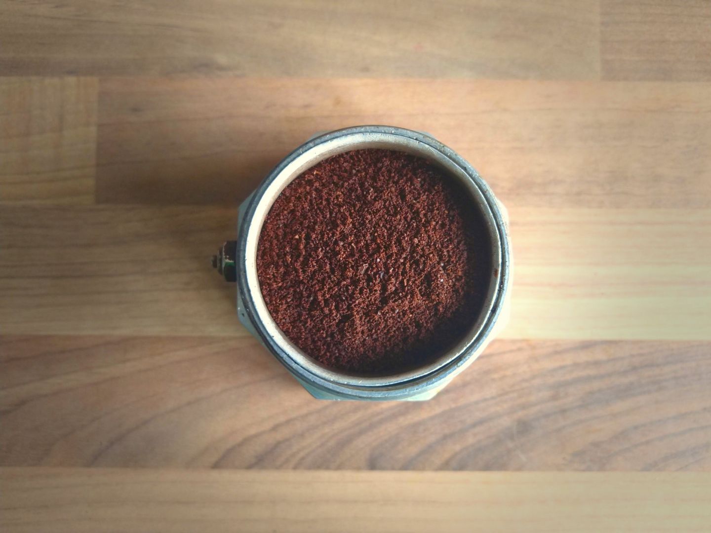 The bottom half of a moka pot showing the dry ground coffee