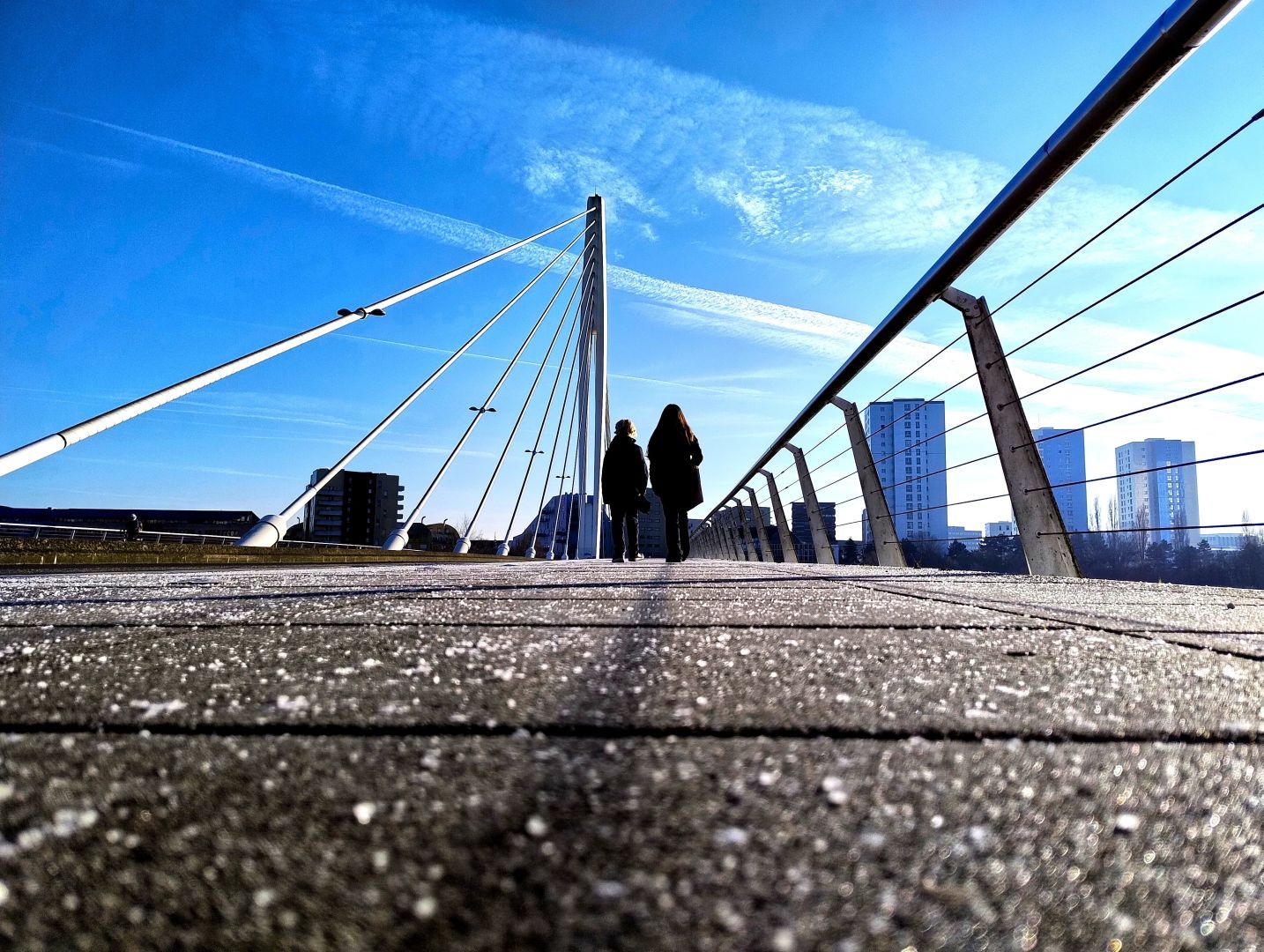 photo of 2 kids taken from behind walking on the footpath crossing a bridge