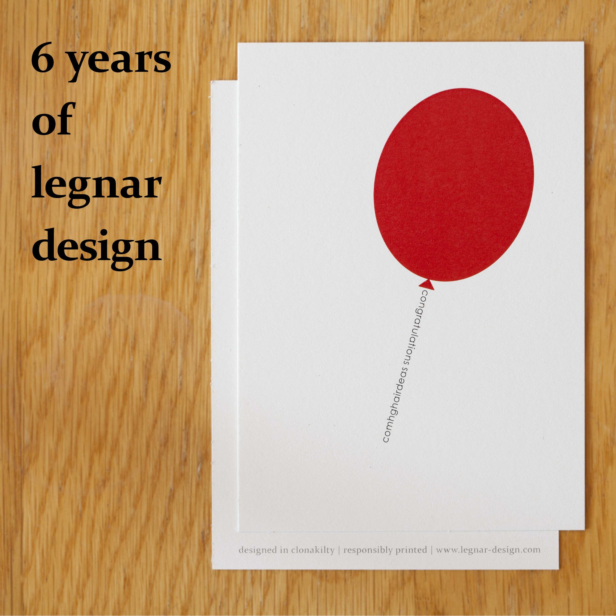 the image shows a photograph of a greeting card on a wooden desk and a headline in the top left corner. the headline says '6 years of legnar design' in black bold lower case letters. the greeting card shows a minimally designed red ballon, which string is formed by the word 'congratulations' and it's irish translation.